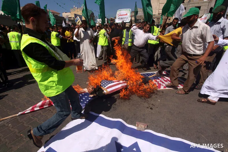 Palestinians burn the Israeli and the U.S. flags during a demonstration against the controversial film 'Innocence of Muslims' in Khan Younis southern Gaza strip, on September 14, 2012. The controversial low budget film r...