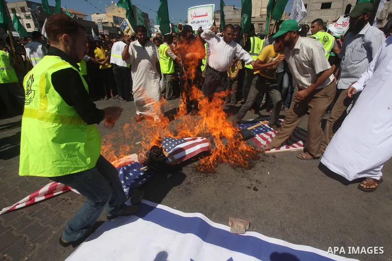 Palestinians burn the Israeli and the U.S. flags during a demonstration against the controversial film 'Innocence of Muslims' in Khan Younis southern Gaza strip, on September 14, 2012. The controversial low budget film r...