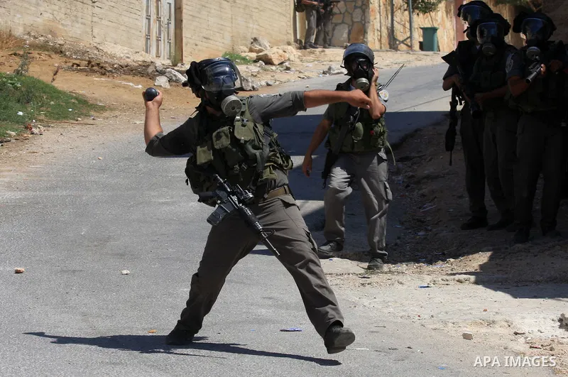 An Israeli border policeman throw a tear gas canister at Palestinian protesters during a demonstration against the expropriation of Palestinian land by Israel in the village of Kafr Qaddum, near the West Bank city of Nab...