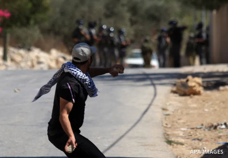A Palestinian protester throws stones at Israeli troops during a demonstration against the expropriation of Palestinian land by Israel in the village of Kafr Qaddum, near the West Bank city of Nablus, on Sept. 14, 2012....