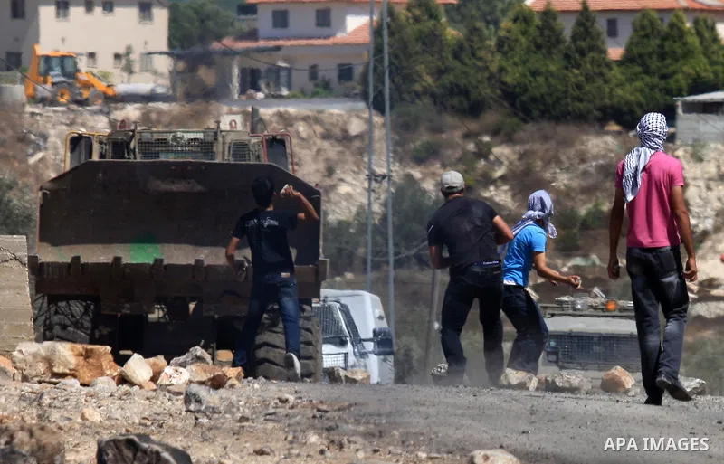 Palestinian protesters throw stones at Israeli bulldozer during a demonstration against the expropriation of Palestinian land by Israel in the village of Kafr Qaddum, near the West Bank city of Nablus, on Sept. 14, 2012....