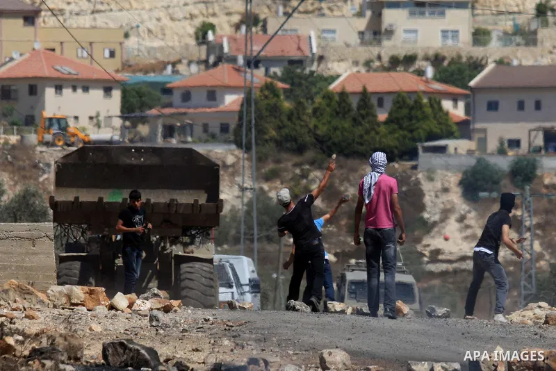 Palestinian protesters throw stones at Israeli bulldozer during a demonstration against the expropriation of Palestinian land by Israel in the village of Kafr Qaddum, near the West Bank city of Nablus, on Sept. 14, 2012....