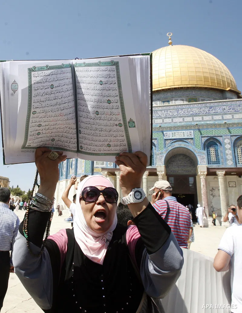 A Palestinian woman holds up a copy of Holy Qur'an during a demonstration against the controversial film 'Innocence of Muslims' in front of al-Aqsa Mosqe in Jerusalem, on September 14, 2012. The controversial low budget...