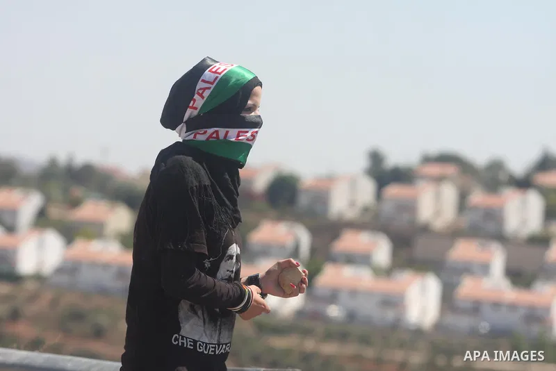 A Palestinian youth throws stones at an Israeli troops during clashes at a weekly protest against a nearby Jewish settlement, in the West Bank village of Nabi Saleh, near Ramallah, on Friday, Sept 14, 2012. The weekly de...