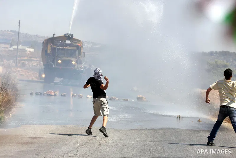 Palestinians throw stones at an Israeli foul smelling water cannon during clashes at a weekly protest against a nearby Jewish settlement, in the West Bank village of Nabi Saleh, near Ramallah, on Friday, Sept 14, 2012. T...