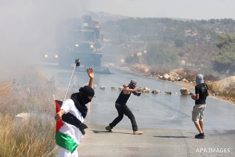 Palestinians throw stones at an Israeli foul smelling water cannon during clashes at a weekly protest against a nearby Jewish settlement, in the West Bank village of Nabi Saleh, near Ramallah, on Friday, Sept 14, 2012. T...