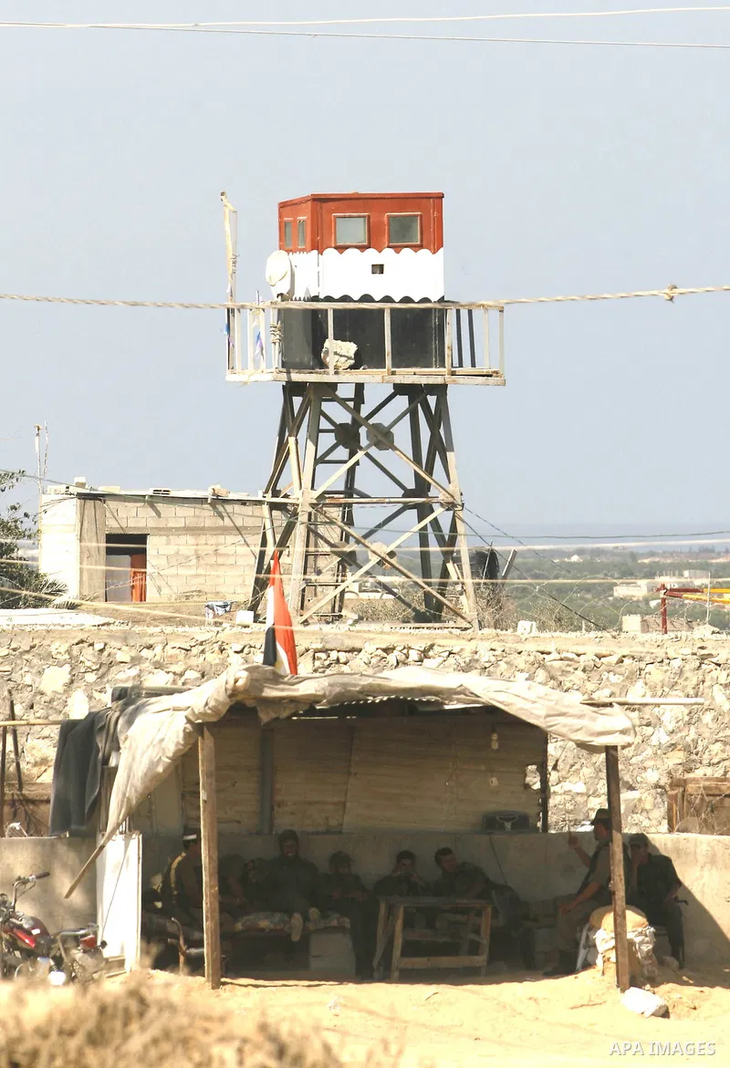 Palestinian border police take a break in a tent in front of the smuggling tunnels along the Gaza-Egypt border in Rafah,in the southern Gaza Strip, back, Egyptian control tower on Sept. 15, 2012. The tunnels trade, which...