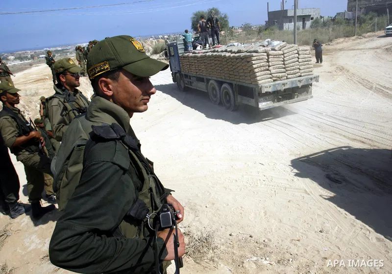 Palestinians ride a lorry carries building materials while Palestinian border police stand along the Gaza-Egypt border in Rafah, in the southern Gaza Strip, on Sept. 15, 2012. The tunnels trade, which analysts estimate i...