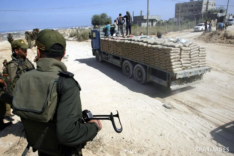 Palestinians ride a lorry carries building materials while Palestinian border police stand along the Gaza-Egypt border in Rafah, in the southern Gaza Strip, on Sept. 15, 2012. The tunnels trade, which analysts estimate i...