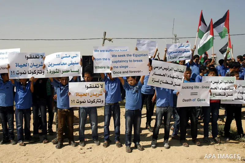 Palestinian children hold national flags and placards during a protest against the Egyptian decision to close the smuggling tunnels along the Gaza-Egypt border in Rafah, in the southern Gaza Strip, on Sept. 15, 2012. The...