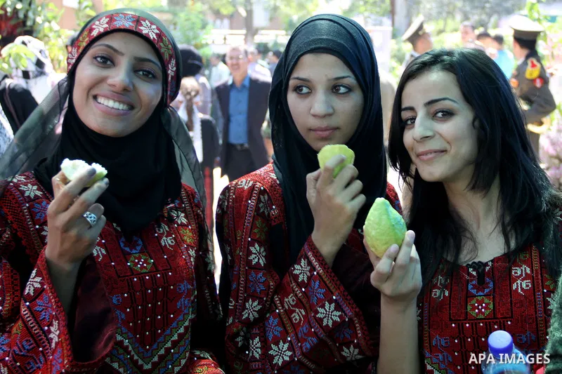 Palestinian girls wear traditional dress and eat guava fruits, during the guava festival in the West Bank city of Qalqilya, Sept. 17, 2012. Photo by Nedal Eshtayah