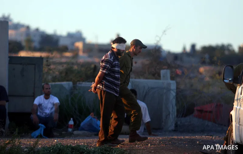 An Israeli soldier detains a Palestinian man on the Atara checkpoint in the West Bank city of Ramallah on September 17, 2012. Photo by Issam Rimawi
