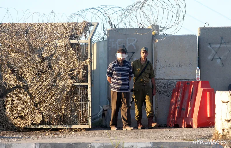 An Israeli soldier detains a Palestinian man on the Atara checkpoint in the West Bank city of Ramallah on September 17, 2012. Photo by Issam Rimawi