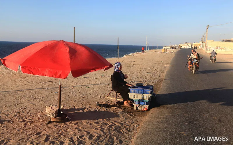 A Palestinian woman displays fish to sale it on the beach of Gaza city, Sept. 18, 2012 . Photo by Majdi Fathi