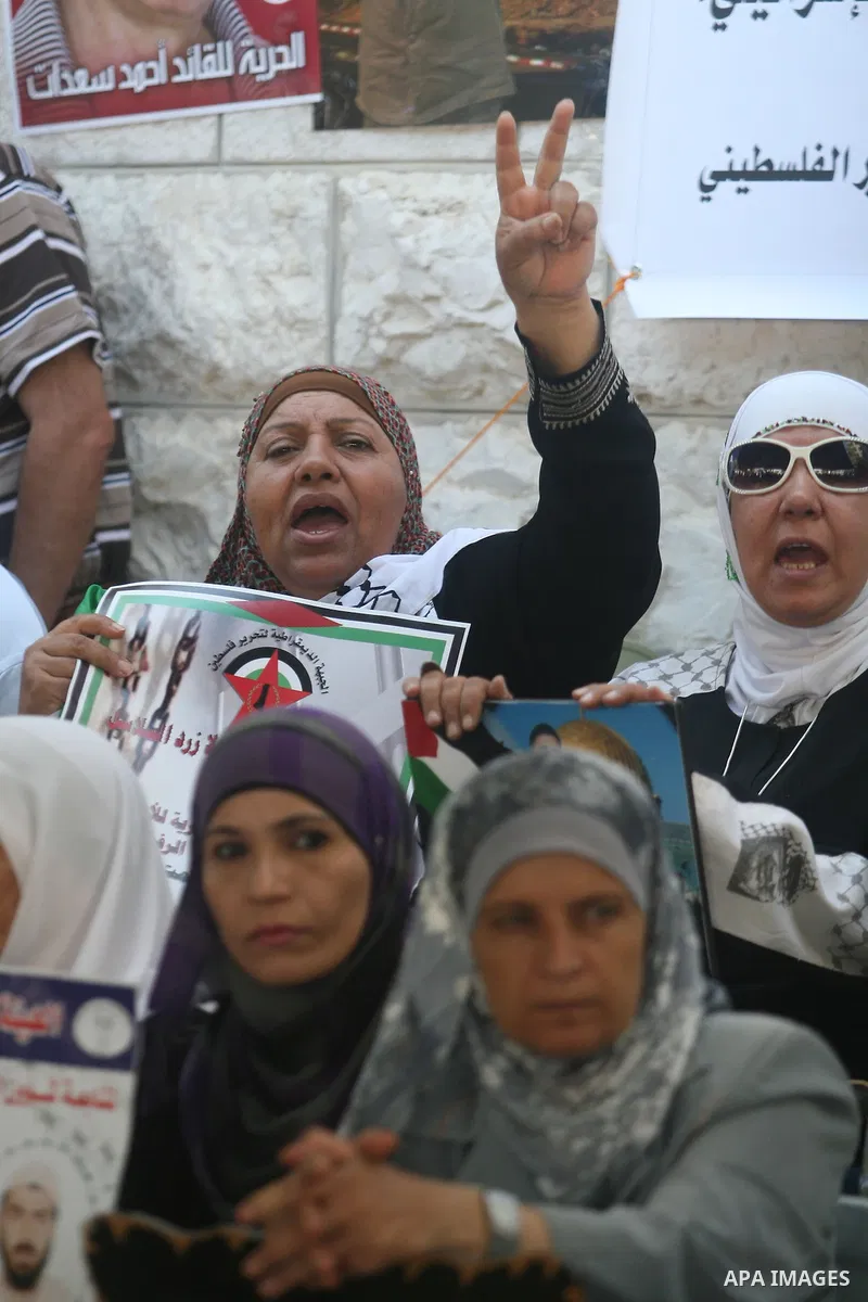 Palestinian women hold pictures of prisoners held in Israeli jails during a sit-in outside the Red Crescent offices near the West Bank city of Ramallah on September 18, 2012 in solidarity with hunger-striking detainees h...