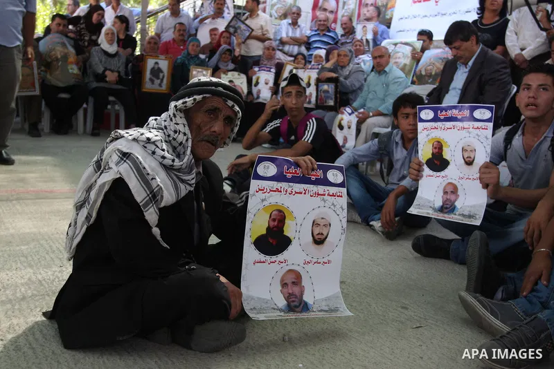 Palestinians hold pictures of prisoners held in Israeli jails during a sit-in outside the Red Crescent offices near the West Bank city of Ramallah on September 18, 2012 in solidarity with hunger-striking detainees held b...
