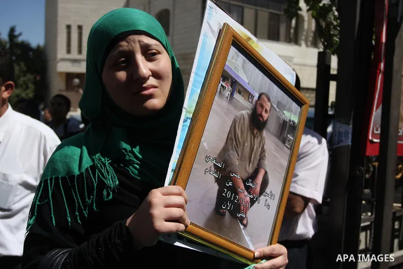 A Palestinian woman holds picture of prisoner held in Israeli jails during a sit-in outside the Red Crescent offices near the West Bank city of Ramallah on September 18, 2012 in solidarity with hunger-striking detainees...
