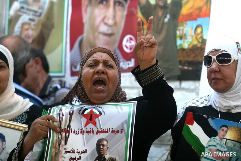 Palestinian women hold pictures of prisoners held in Israeli jails during a sit-in outside the Red Crescent offices near the West Bank city of Ramallah on September 18, 2012 in solidarity with hunger-striking detainees h...