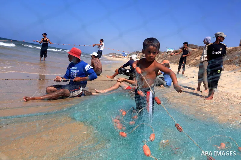 A Palestinian boy helps his father to tow his trawl from the sea in Deir al-Balah Palestinian refugee camp, central of Gaza Strip, on September 19, 2012. Photo by Majdi Fathi