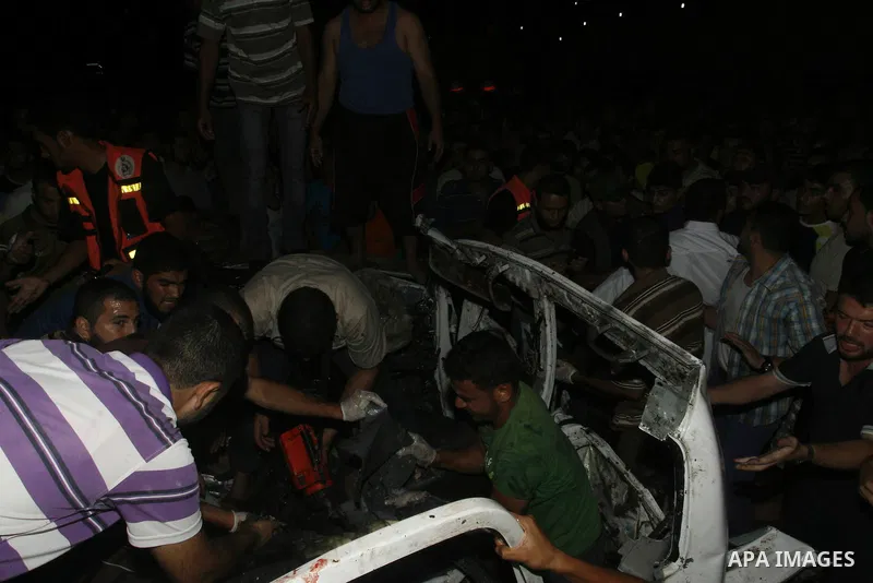 Palestinians gather around the wreckage of a car targeted by an Israeli aircraft in the town of Rafah in southern Gaza Strip on September 19, 2012. An Israeli air strike on the Gaza Strip killed two Palestinians and woun...