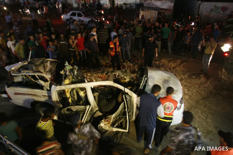 Palestinians gather around the wreckage of a car targeted by an Israeli aircraft in the town of Rafah in southern Gaza Strip on September 19, 2012. An Israeli air strike on the Gaza Strip killed two Palestinians and woun...