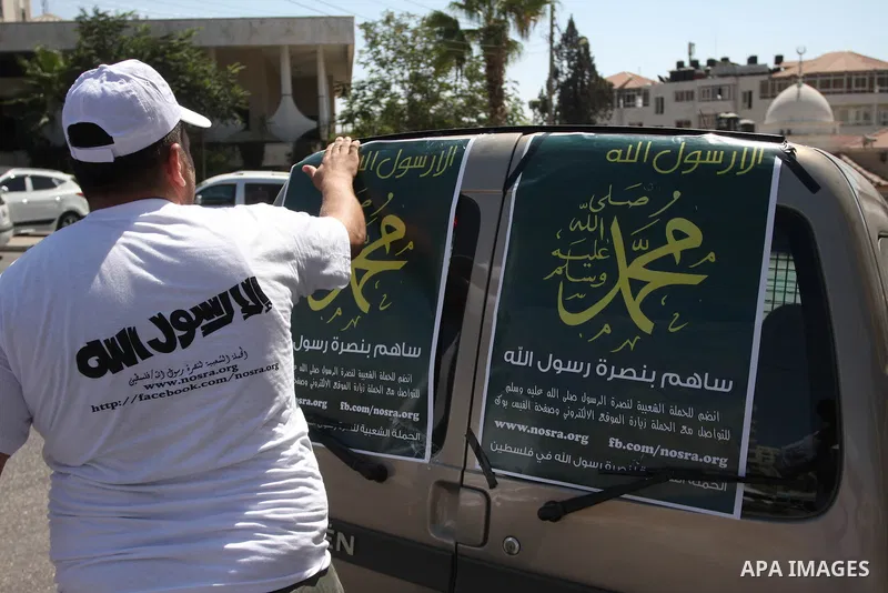A Palestinians youth pastes a poster on acar reading in Arabic "anyone but prophet Muhammad" during a campaign called by Palestinian activists against the anti-Islam movie entitled 'Innocence of Muslims' made in the U.S....
