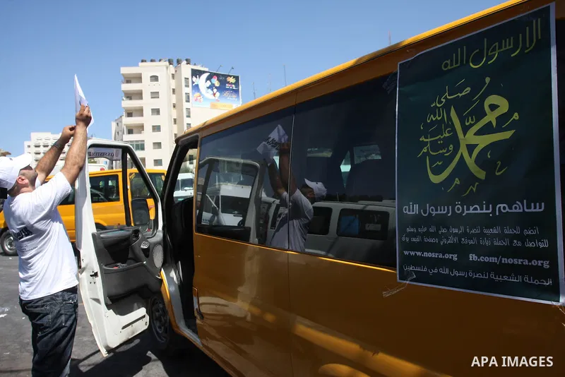 A Palestinians youth pastes a poster on acar reading in Arabic "anyone but prophet Muhammad" during a campaign called by Palestinian activists against the anti-Islam movie entitled 'Innocence of Muslims' made in the U.S....