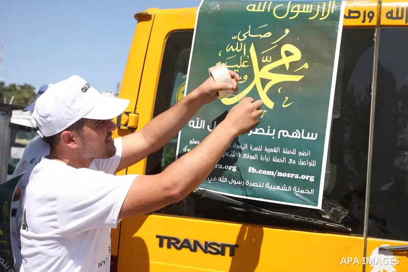 A Palestinians youth pastes a poster on acar reading in Arabic "anyone but prophet Muhammad" during a campaign called by Palestinian activists against the anti-Islam movie entitled 'Innocence of Muslims' made in the U.S....