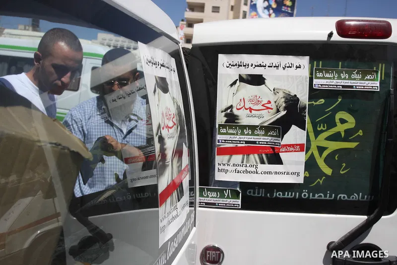 A Palestinians youth pastes a poster on acar reading in Arabic "anyone but prophet Muhammad" during a campaign called by Palestinian activists against the anti-Islam movie entitled 'Innocence of Muslims' made in the U.S....