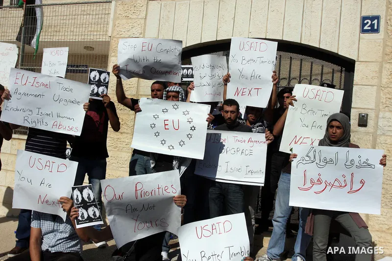 Palestinian activists hold placards as they block the entrance of the EU police office during a protest refusal to the policy of European Union toward Palestinian issue and the prisoners in the Israeli jails, in the West...