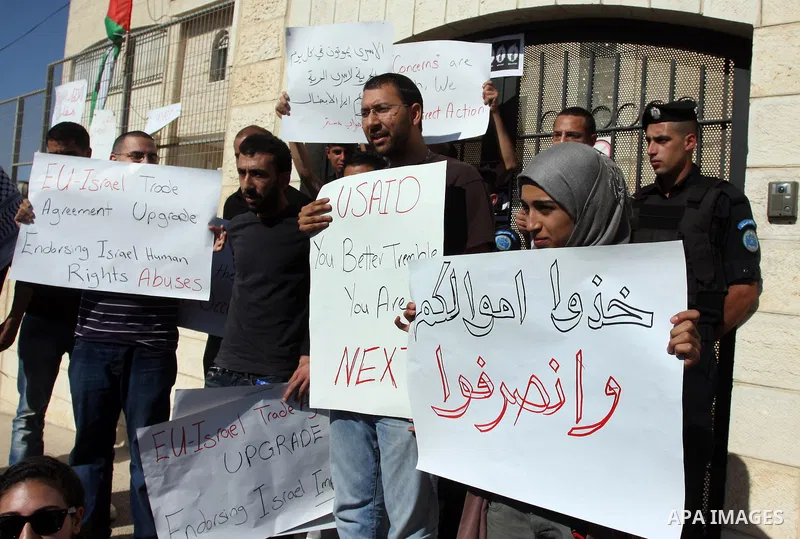 Palestinian activists hold placards as they block the entrance of the EU police office during a protest refusal to the policy of European Union toward Palestinian issue and the prisoners in the Israeli jails, in the West...