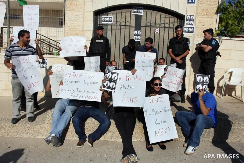 Palestinian activists hold placards as they block the entrance of the EU police office during a protest refusal to the policy of European Union toward Palestinian issue and the prisoners in the Israeli jails, in the West...