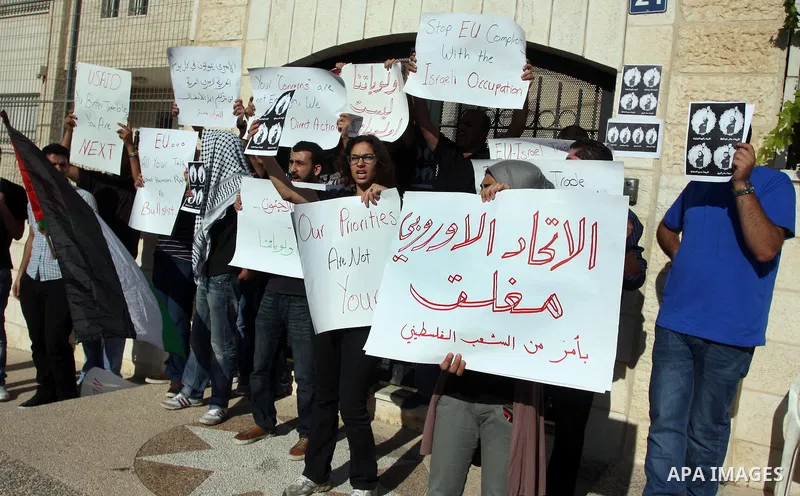 Palestinian activists hold placards as they block the entrance of the EU police office during a protest refusal to the policy of European Union toward Palestinian issue and the prisoners in the Israeli jails, in the West...