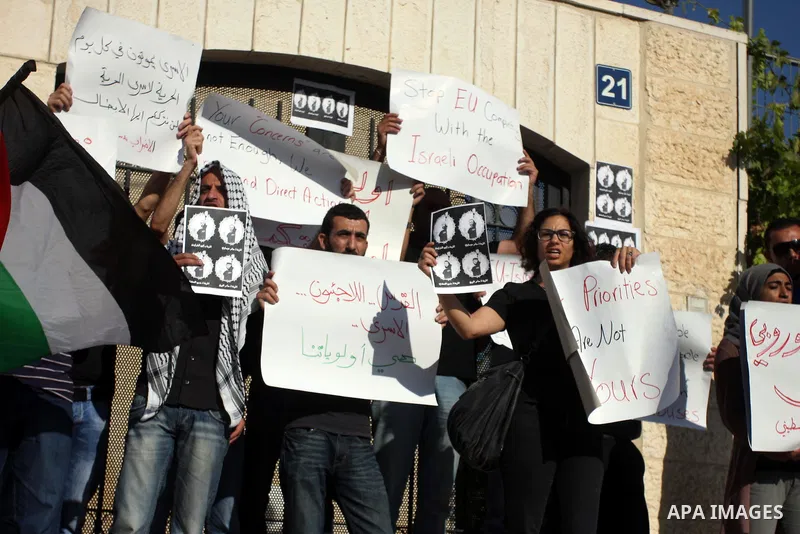 Palestinian activists hold placards as they block the entrance of the EU police office during a protest refusal to the policy of European Union toward Palestinian issue and the prisoners in the Israeli jails, in the West...