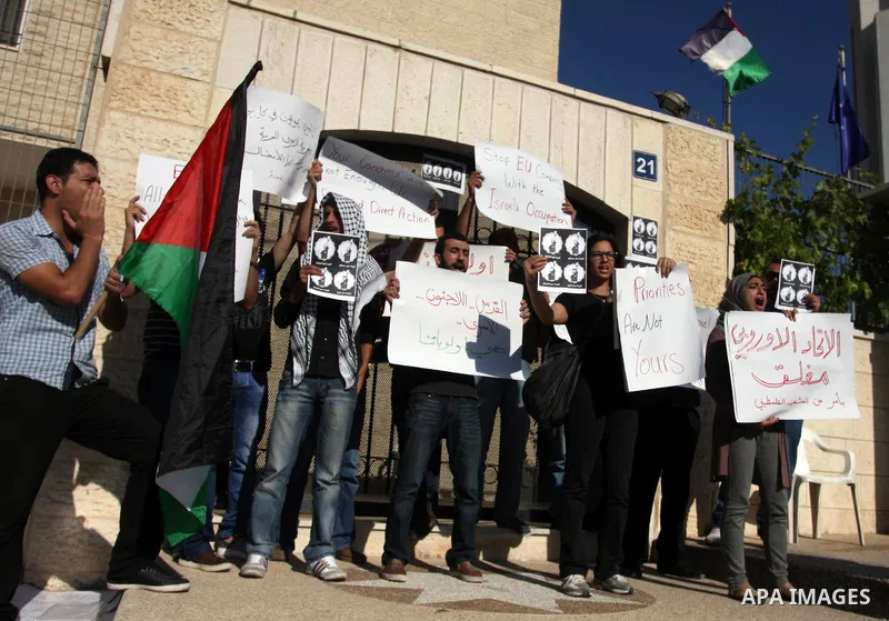 Palestinian activists hold placards as they block the entrance of the EU police office during a protest refusal to the policy of European Union toward Palestinian issue and the prisoners in the Israeli jails, in the West...