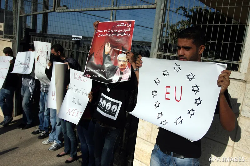 Palestinian activists hold placards as they block the entrance of the EU police office during a protest refusal to the policy of European Union toward Palestinian issue and the prisoners in the Israeli jails, in the West...