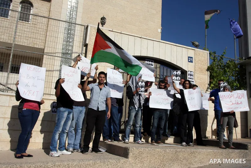 Palestinian activists hold placards as they block the entrance of the EU police office during a protest refusal to the policy of European Union toward Palestinian issue and the prisoners in the Israeli jails, in the West...