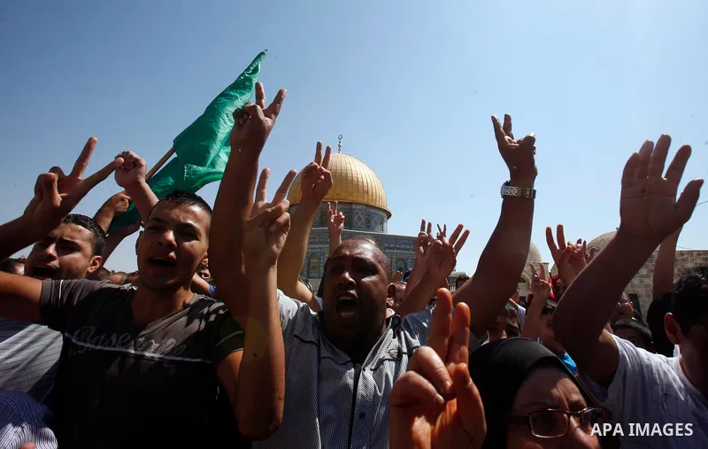 Palestinians wave flags and shout slogans during a protest against an anti-Islam movie made in the U.S. and French cartoons said to insult the Prophet Muhammad in Jerusalem's Old City, Sept. 21, 2012. Photo by Mahfouz Ab...