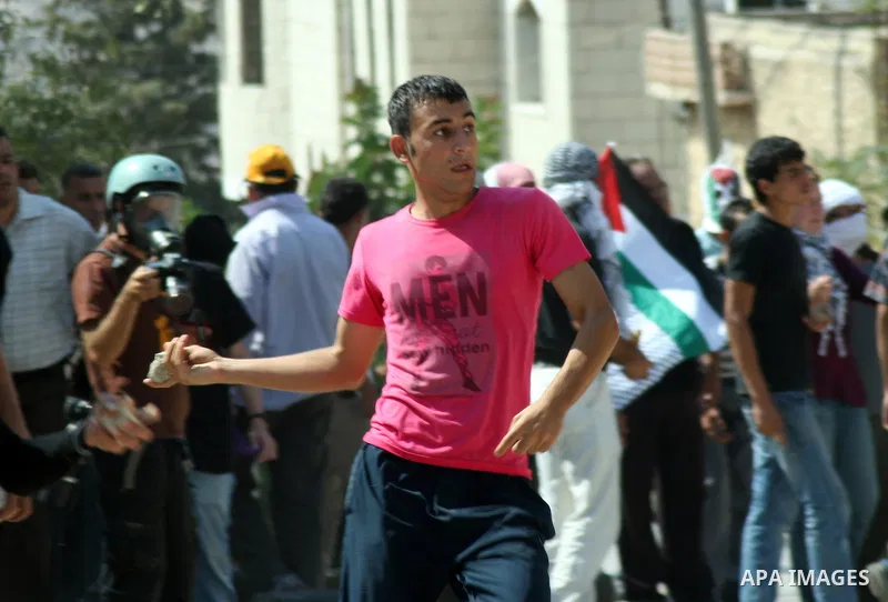 A Palestinian protester throws stones at Israeli soldiers during a demonstration against the expropriation of Palestinian land by Israel in the village of Kfar Qaddum, near the West Bank city of Nablus, on september 21,...