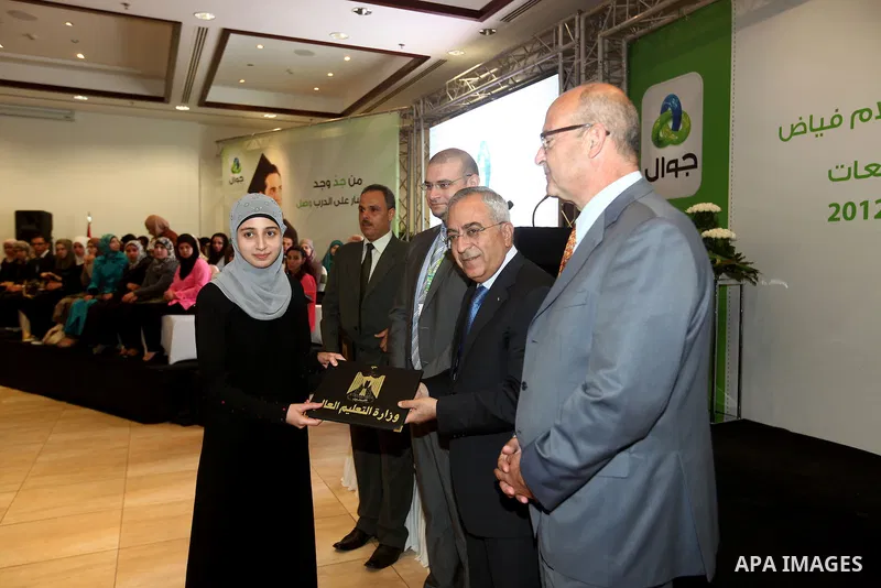 Palestinian Prime Minister Salam Fayyad honors a student during the ceremony of the honoring the superior students in the Palestinian Universities in the year 2012, in the West Bank city of Ramallah, Sept. 23, 2012. Phot...