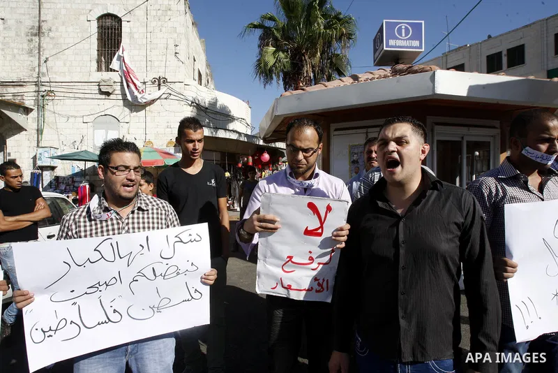 Palestinian protesters hold placareds during a protest against the Paris Protocol and the high cost of living in the West Bank city of Nablus on September 24, 2012. Photo by Nedal Eshtayah