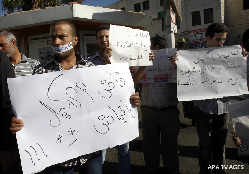 Palestinian protesters hold placareds during a protest against the Paris Protocol and the high cost of living in the West Bank city of Nablus on September 24, 2012. Photo by Nedal Eshtayah
