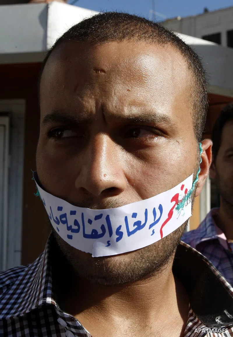 A Palestinian protester with a strip of paper reading "Yes for cancel the Paris Protocol" during a protest against both key accords, which govern economic ties between Palestinians and Israelis, in the West Bank city of...