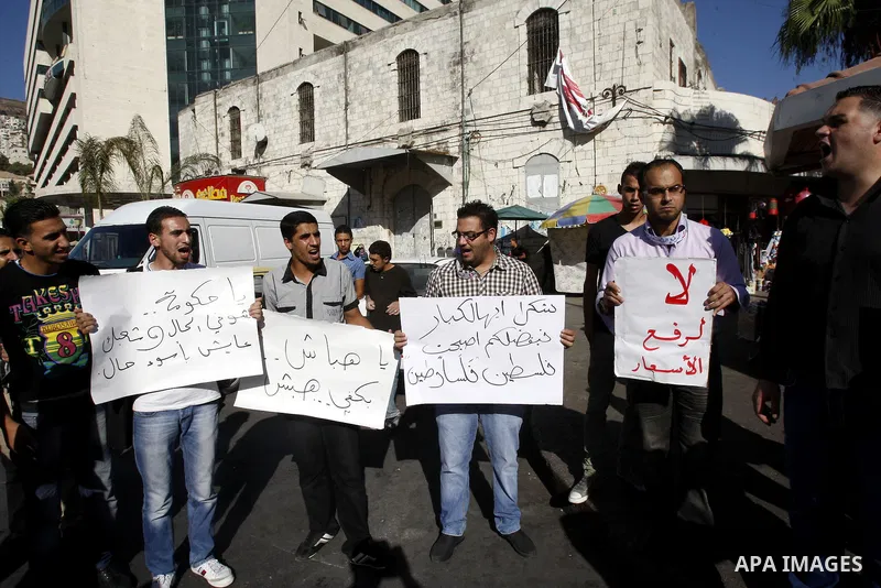 Palestinian protesters hold placareds during a protest against the Paris Protocol and the high cost of living in the West Bank city of Nablus on September 24, 2012. Photo by Nedal Eshtayah