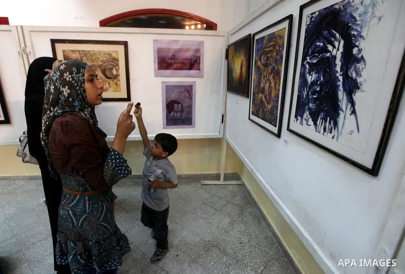 Palestinians look at paintings during an abstract painting show in Gaza city, on 24 September 2012. Photo by Majdi Fathi