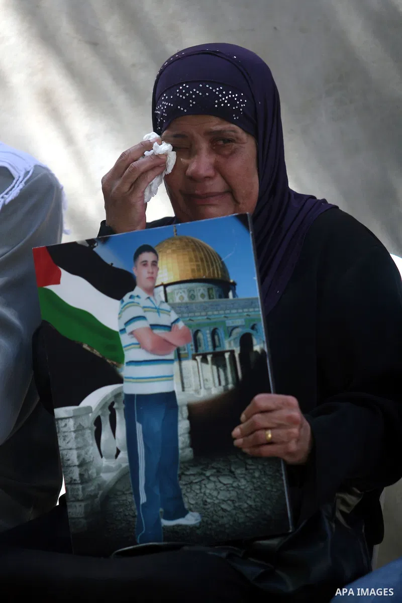 A Palestinian woman holds picture of a prisoner held in Israeli jails during a sit-in outside the Red Crescent offices near the West Bank city of Ramallah on September 25, 2012 in solidarity with hunger-striking detainee...