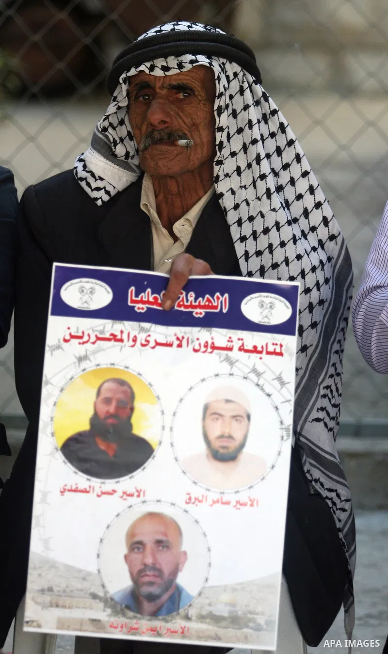 A Palestinian man holds picture of a prisoner held in Israeli jails during a sit-in outside the Red Crescent offices near the West Bank city of Ramallah on September 25, 2012 in solidarity with hunger-striking detainees...
