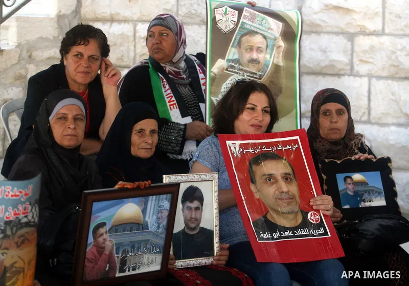 Palestinian women hold pictures of prisoners held in Israeli jails during a sit-in outside the Red Crescent offices near the West Bank city of Ramallah on September 25, 2012 in solidarity with hunger-striking detainees h...