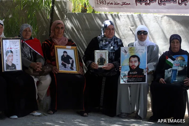 Palestinian women hold pictures of prisoners held in Israeli jails during a sit-in outside the Red Crescent offices near the West Bank city of Ramallah on September 25, 2012 in solidarity with hunger-striking detainees h...