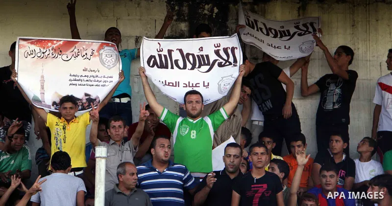 Palestinian fans hold placards reading Arabic "Anyone but prophet Muhammad" the premier league soccer match between the team of al-Shatie and the team of al-Shijaiain Gaza city on 23 September 2012. Photo by Alaa Shamaly